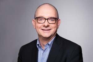 Porträtfoto von Andre Stinka vor grauem Hintergrund