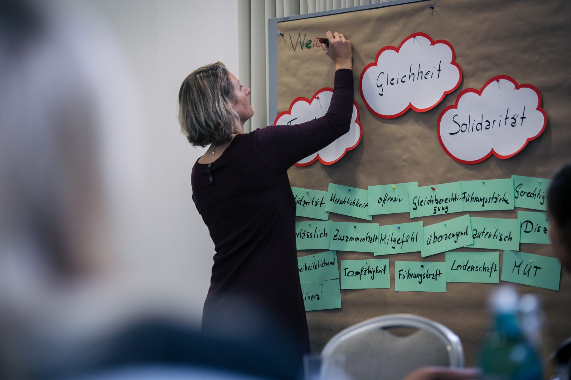 Eine Teilnehmerin beschriftet ein Plakat mit den Überschriften "Gleichheit" und "Solidarität"