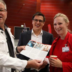 Dörte Schall und weitere Delegierte zeigen einen Prospekt in die Kamera