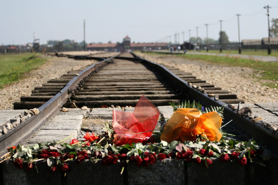 Mit Blumen belegtes Bahngleis vor dem Eingang des KZ Auschwitz-Birkenau
