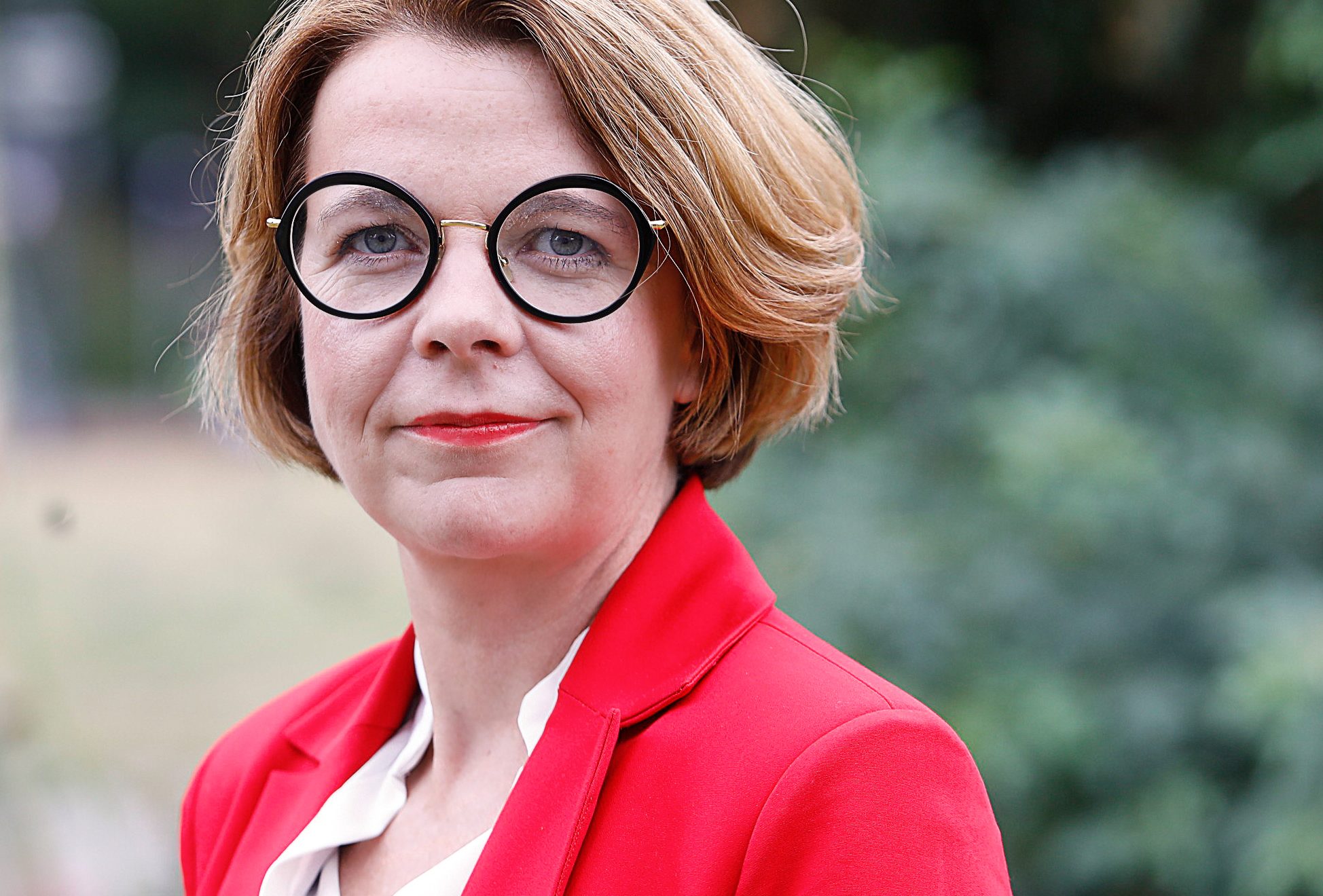 Porträtfoto von Nadja Lüders. Sie trägt ein weißes Hemd und ein rotes Jackett.
