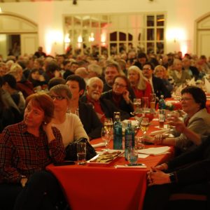 Politischer Aschermittwoch im Saal der Traditionsgaststätte "Freischütz" in Schwerte. Der Saal ist voll mit Menschen. Sie sitzen an langen Tafeln und schauen gebannt auf die Bühne und hören den Rednern zu.